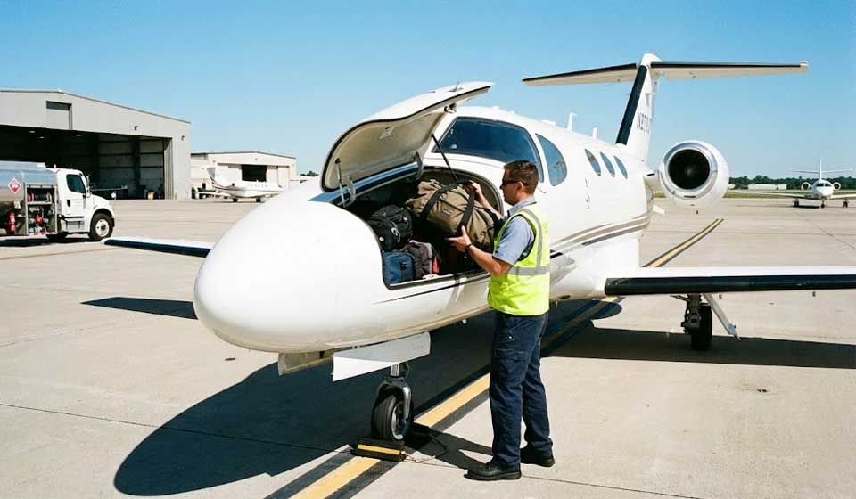 Loading Luggage Into The Nose Compartment Of A Light Private Jet.